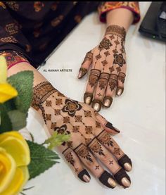 a woman's hands with hennap and flowers on the table in front of her