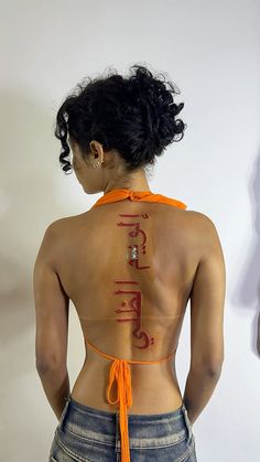 the back of a woman's body with an orange ribbon around her neck and writing on it