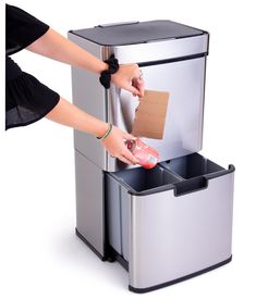 a woman is opening the trash can with her hand and cardboard sticking out of it