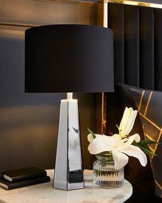 a white flower sitting on top of a table next to a lamp