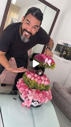 a man standing in front of a table with flowers on it and a cake made out of pink roses