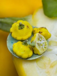 a spoon with some food on it sitting in front of yellow bananas and other fruit