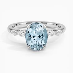 an oval aqua blue topazte and diamond ring with white diamonds on the sides