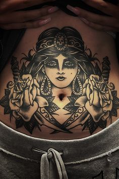 a woman's stomach with tattoos on it and her hands behind her back, holding a cell phone