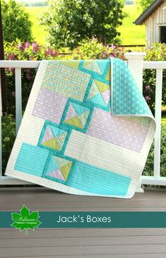 a quilted blanket sitting on top of a porch next to a white fence and flowers