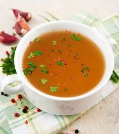 a white bowl filled with soup sitting on top of a green and white towel next to garlic