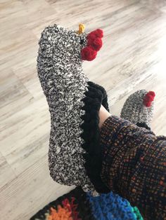 someone's feet wearing slippers with crochet and pom - poms