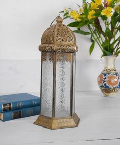 a decorative lantern sitting on top of a table next to two books and a vase with flowers in it