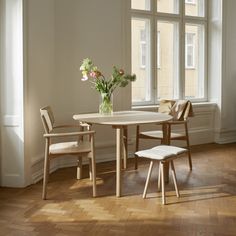 a table and chairs in front of a window with flowers on the table next to it