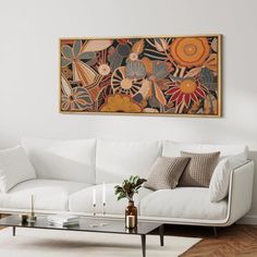 a living room with a white couch, coffee table and large painting on the wall