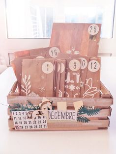 a wooden crate filled with christmas cards and numbers on it's side, next to a window