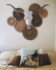 a bed topped with lots of pillows next to a wall mounted cow skull on the wall