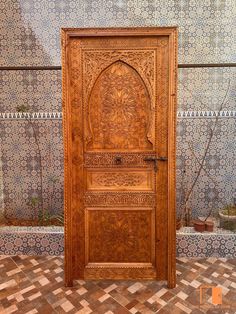 an ornate wooden door in the middle of a tiled floored area with potted plants