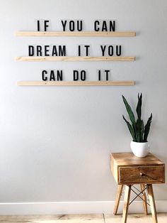 a plant sitting on top of a wooden table next to a sign that says if you can dream it you can do it