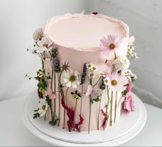 a pink cake decorated with flowers and daisies