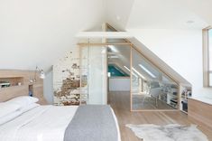 an attic bedroom with white walls and wood flooring, exposed brickwork on the wall