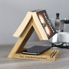 a wooden stand with a book on top of it and a cell phone in the middle