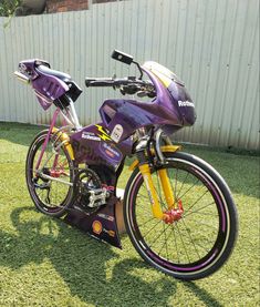 a purple and yellow motorcycle parked in the grass