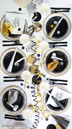 the table is set with black and white plates, silverware, and napkins