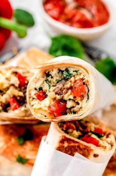 an open burrito sitting on top of a cutting board next to tomatoes and basil