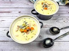 two bowls filled with soup on top of a wooden table