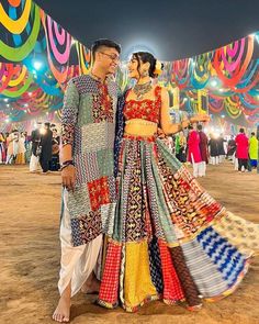 a man and woman standing next to each other in front of a tent with colorful decorations