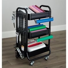 a black cart with several different colored papers on it and scissors in the middle, next to a white wall