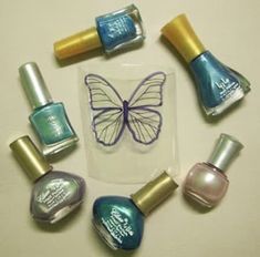 various nail polishes are arranged in a circle with a butterfly on the top and bottom