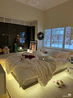 a large bed sitting in the middle of a living room next to two windows with christmas decorations on them