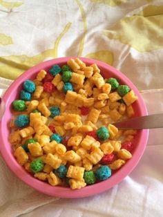 a pink bowl filled with cereal on top of a bed