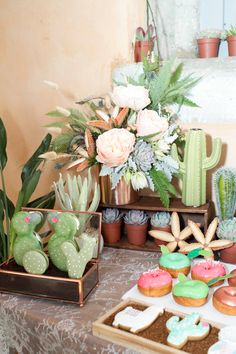 a table topped with lots of different types of doughnuts and succulents