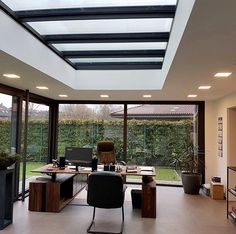 a home office with glass walls and skylights