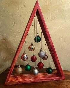 a wooden christmas tree with ornaments hanging from it's sides and on the bottom