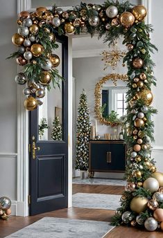 a christmas wreath with gold and silver ornaments hanging from it's sides in front of a door