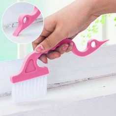 a hand holding a pink brush on top of a window sill