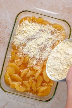 a person holding a spoon over some food in a glass dish with powdered sugar on top