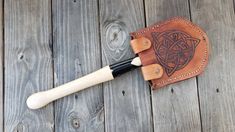 a leather tool case with an intricate design on the front and side, sitting on a wooden surface