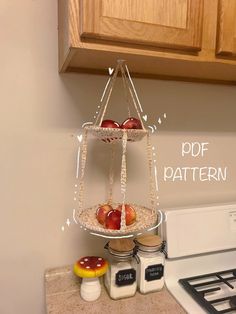 two apples are sitting on top of a hanging basket in the kitchen, and another apple is next to it