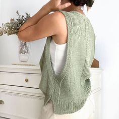 a woman standing in front of a dresser holding a cell phone up to her ear