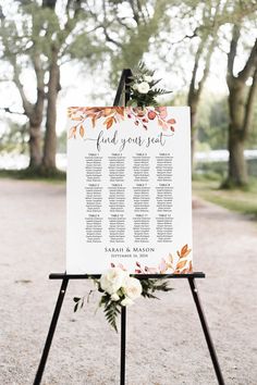 a white sign with greenery and flowers on it