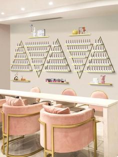 the interior of a nail salon with pink velvet chairs and gold accents on the wall