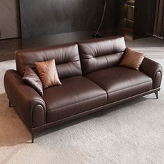 a brown leather couch sitting on top of a carpeted floor next to a lamp