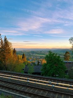 a train track with trees and buildings in the background at sunset or sunrise, as seen from above