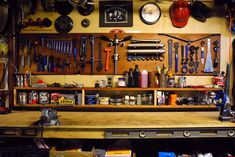 a workbench with lots of tools hanging on the wall and shelves below it