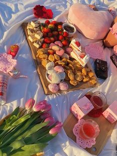 a table topped with lots of different types of food and drinks on top of a white blanket