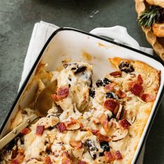 a casserole dish with bacon, cheese and bread in it on a table