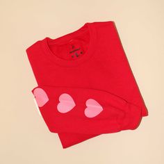 Red crewneck sweatshirt with pink hearts screen printed on the sleeves. Red Long Sleeve Sweater With Heart Print, Red Crew Neck Top With Ribbed Cuffs, Red Crew Neck Sweatshirt With Relaxed Fit, Red Relaxed Fit Crew Sweatshirt, Casual Sweatshirt With Heart Graphic For Loungewear, Red Sweatshirt With Ribbed Cuffs For Loungewear, Cotton Long Sleeve Sweater With Heart Print, Red Heart Print Sweater For Valentine's Day, Red Crew Neck Sweatshirt With Ribbed Cuffs