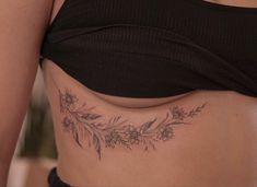 a close up of a woman's stomach with flowers and leaves tattooed on it