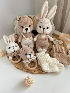 there are knitted animals in the basket on the table next to yarn balls and knitting needles