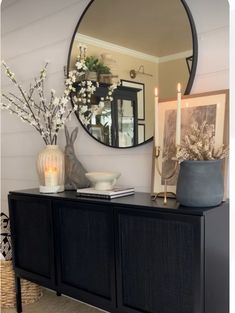 a living room with a large round mirror on the wall next to a black dresser